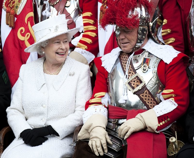 Elizabeth tillsammans med major Paul Champness, ledare för frivilligkompaniet Honorable Artillery, i London i maj 2010. De skrattar gott åt att drottningen hade råkat trassla in sig i majorens 1600-talsuniform.
