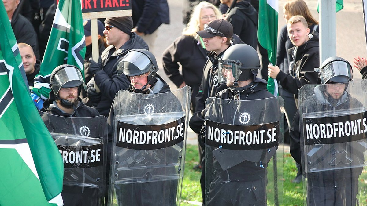 NMR-medlemmar med sköldar och hjälmar under en demonstration. 