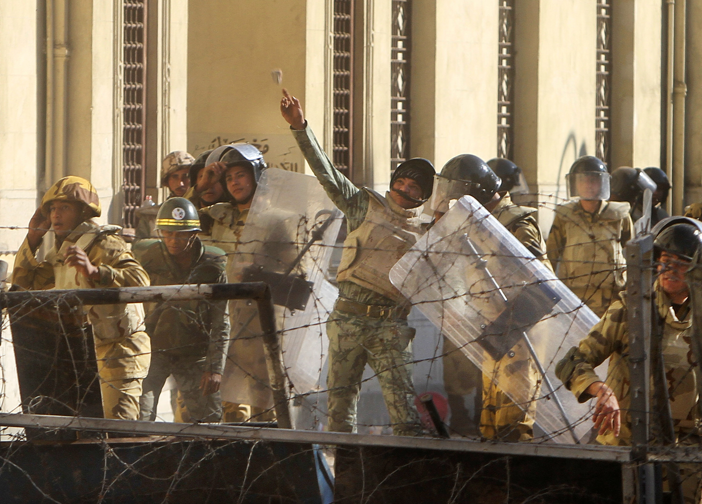 Militärpolis kastar sten på demonstranter. 