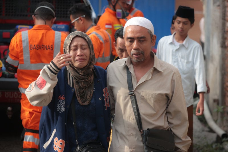 En kvinna gråter i närheten av den kollapsade skolan i indonesiska Sidoarjo.