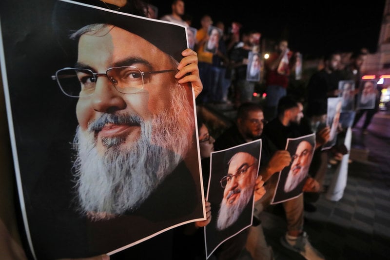 Libanesiska och palestinska män håller upp porträtt på Hizbollahledaren Hassan Nasrallah dagen efter att han dödades i ett israeliskt flygangrepp i september i fjol.