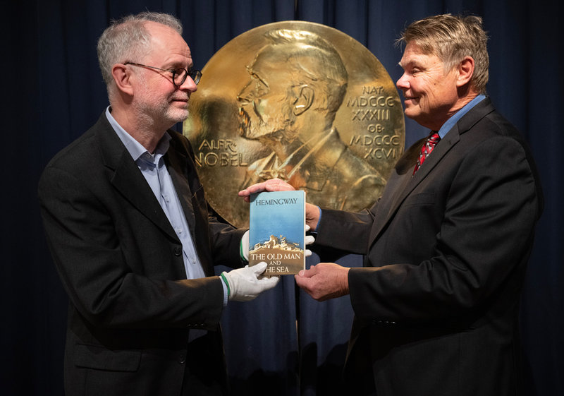Nobelprismuseets intendent Ulf Larsson tar emot boken ”Den gamle och havet” av den amerikanske Hemingway-kännaren Curtis DeBerg.