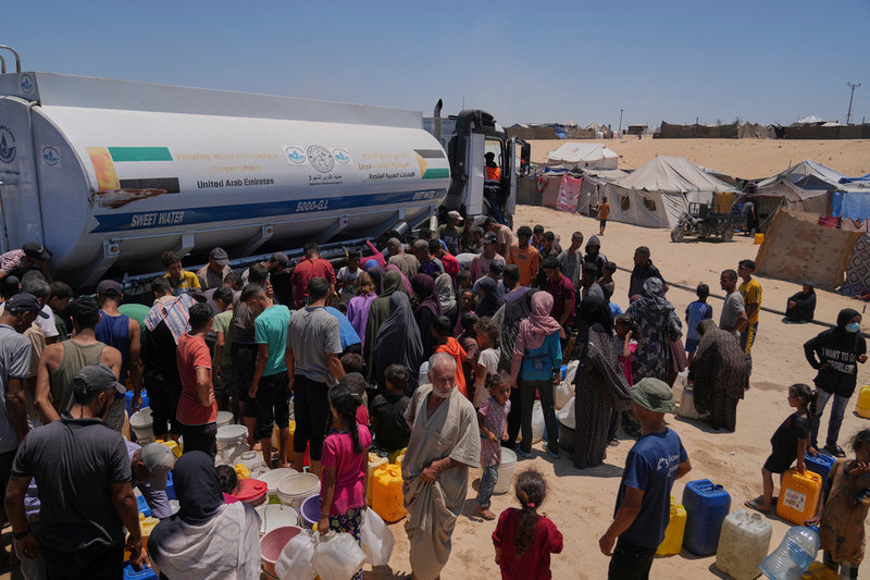 Vatten delas ut i ett tältläger i Khan Yunis i södra Gaza i juli.