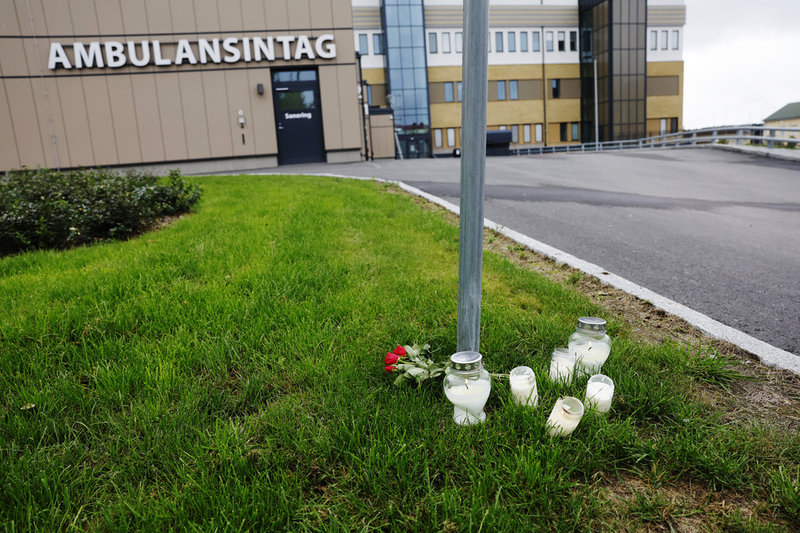 Blommor och ljus utanför ambulansintaget i Hudiksvall, dagen efter det att en ambulanssjukvårdare dödats i tjänsten.