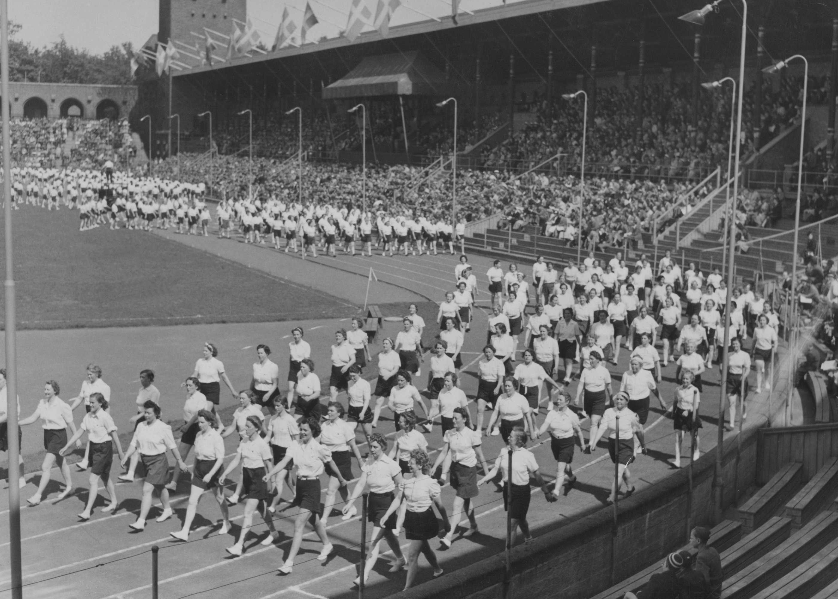 En bild och bildtext från det episka bildarkivet; "Husmorsgymnastiken på frammarsch.
Husmödrarna marscherar ut ur Stockholm Stadion efter en bejublad uppvisning. Parad."