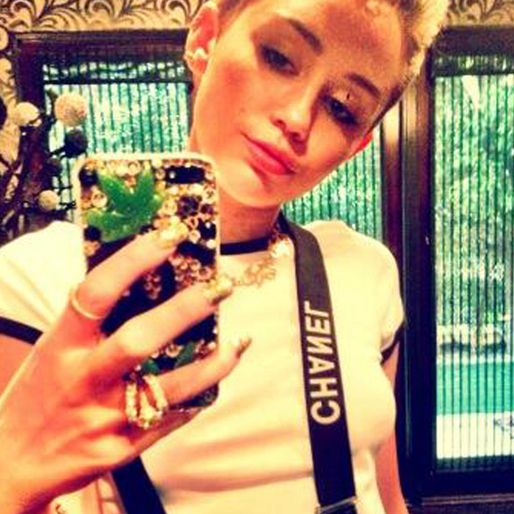 Miley poserar med sitt marijuanalöv-pyntade iPhone-skal. 