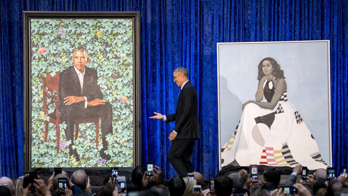 USA:s tidigare president Barack Obama och porträttet på honom av konstnären Kehinde Wiley när målningen presenterades 2018. Till höger det officiella porträttet på Michelle Obama. Arkivbild.