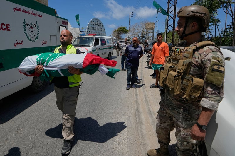 En vårdvolontär bär undan kvarlevor av en av sex personer i en familj som dödades i ett israeliskt flyganfall utanför Tyr. Bilden togs i fredags förra veckan.