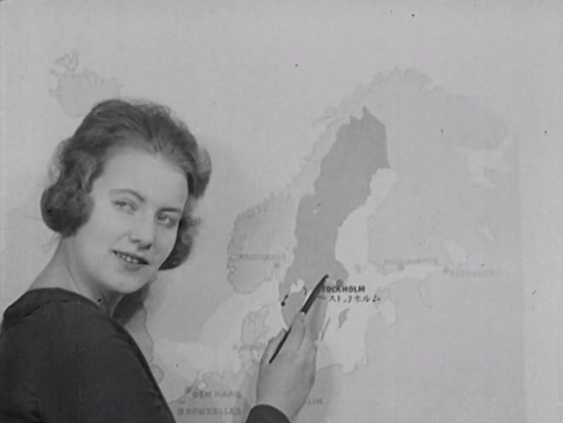 Bild ur en informationsfilm från 1920 där Greta Garbo pekar ut svenska industrier på en karta.