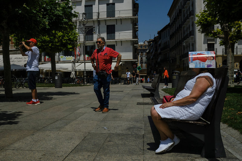 En kvinna försöker svalka sig genom att täcka huvudet med en tidning i Pamplona i Spanien.