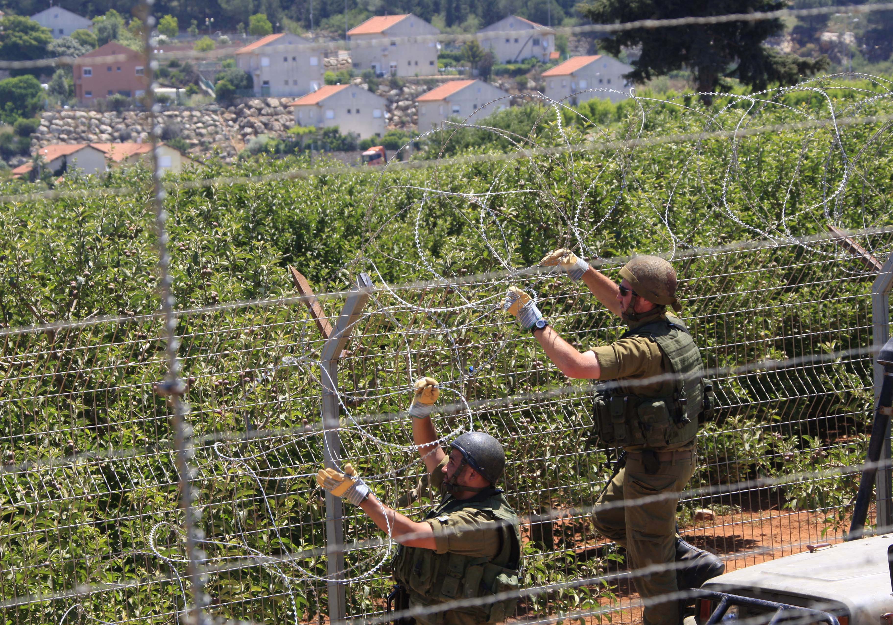 Enligt den israeliska militären ska landet ha beskjutit med raketer tidigt på tisdagen. Bilden: Två israeliska soldater sätter upp taggtråd vid gränsen mot Libanon.