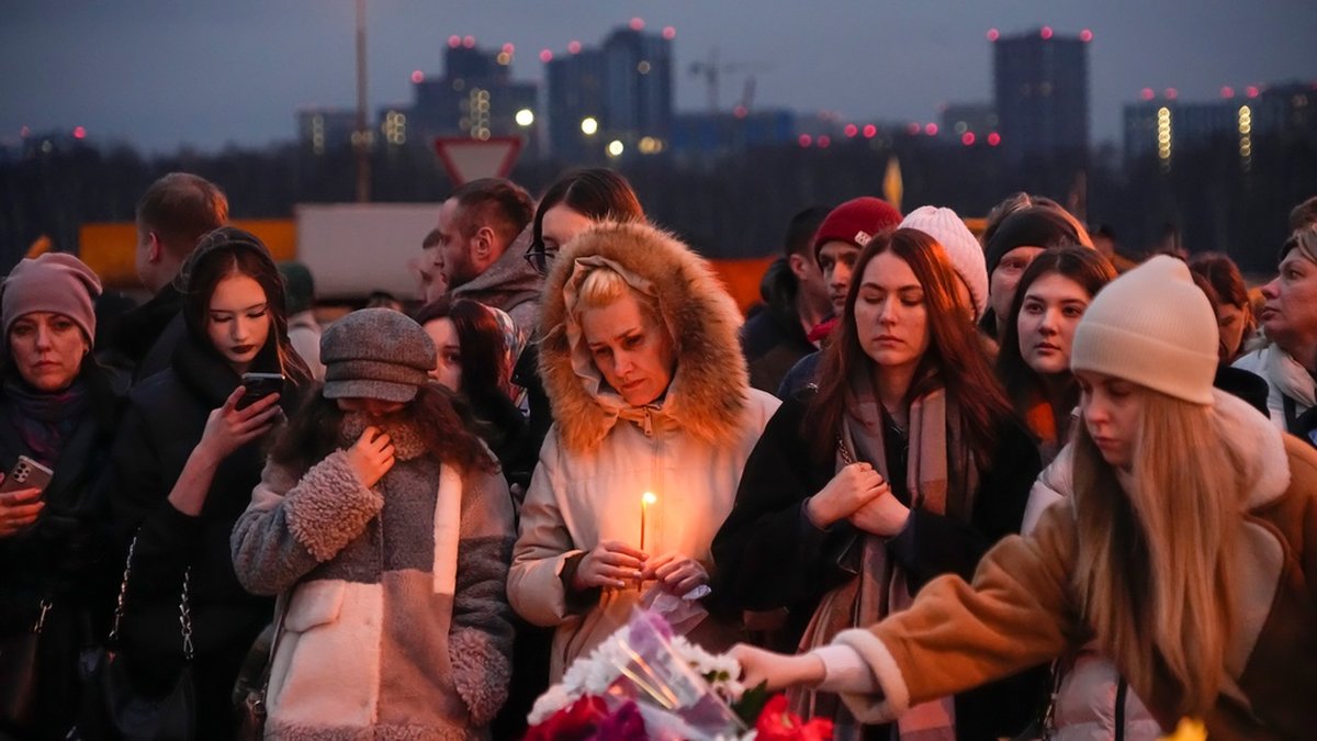 Människor kommer med blommor och ljus till en upprättad minnesplats invid konserthuset i Moskvas västra utkant.