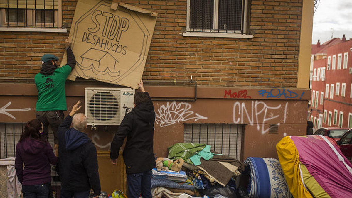 Aktivister placerar en skylt utanför ett hus i Madrid där det står "stoppa vräkningarna".. 