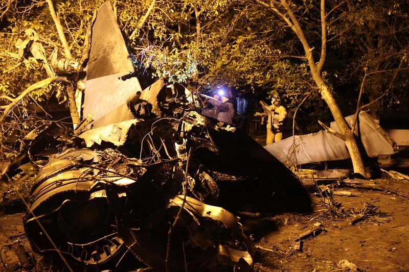 Brandmän inspekterar resterna av stridsflygplanet.