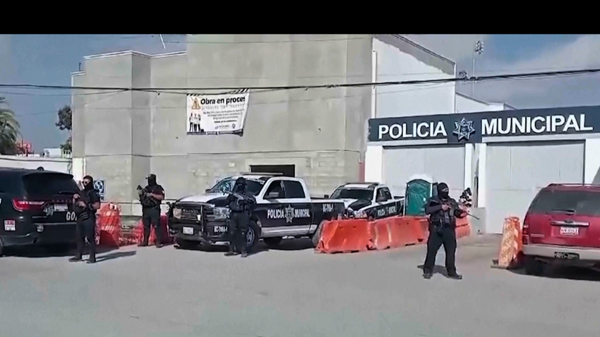 Mexikansk polis vaktar utanför polisstationen i Ensenada där tre personer förhörs i fallet med de saknade turisterna.