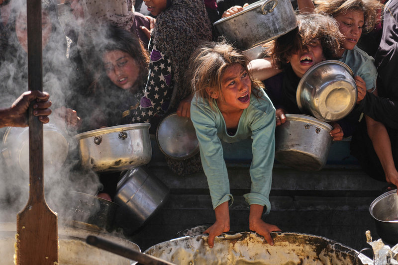 Barn kämpar sig fram för ett donerat mål mat i Khan Yunis i södra Gaza i mitten av maj.