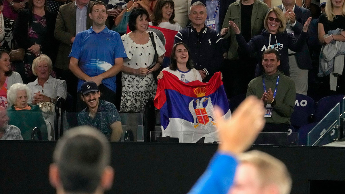 Novak Djokovic vinkar till sin familj – pappa Srdjan är mannen i mitten, bakom den serbiska flaggan – efter segern i Australian Open-kvartsfinalen mot ryssen Andrej Rubljov.