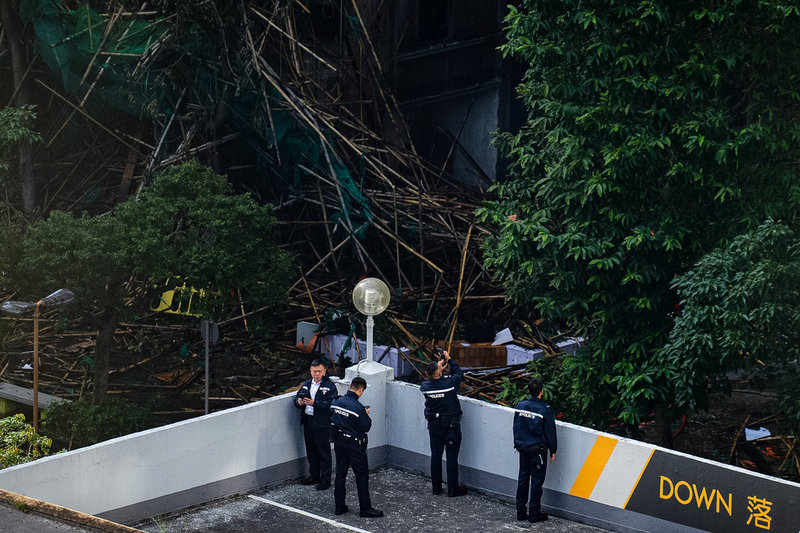 Bambupinnar som användes i byggnadsställningarna ligger i högar utanför en av byggnaderna i komplexet Wang Fuk Court på fredagen.