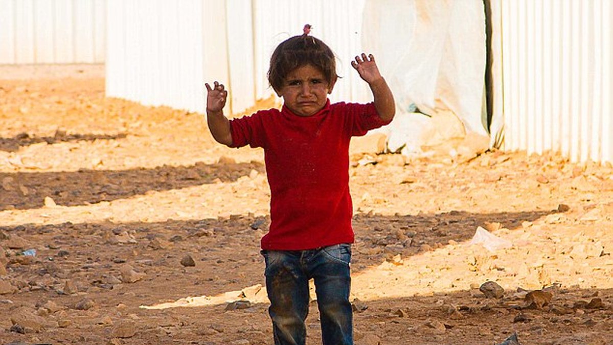 ​Den lilla flickan i ett jordanskt flyktingläger fångades på bild då hon misstar kameran för ett vapen.