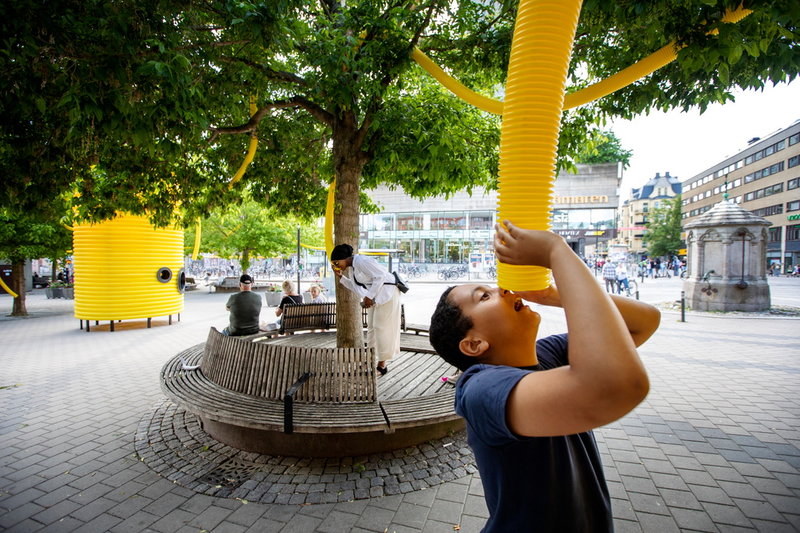 Den italiensk-portugisiska gruppen Moradavaga har byggt upp rörfigurer över torgets träd och sittplatser. I dem kan man prata, som i ett gammalt telefonsnöre, med personer på andra sidan torget. Pressbild.