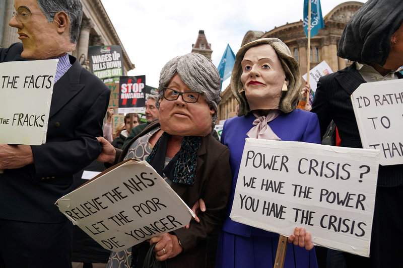 Demonstranter med masker i papier-maché föreställande den brittiska premiärministern Liz Truss till höger, och biträdande premiärminister Therese Coffey till vänster protesterar mot regerings politik utanför regeringspartiet Tories kongress i Birmingham
