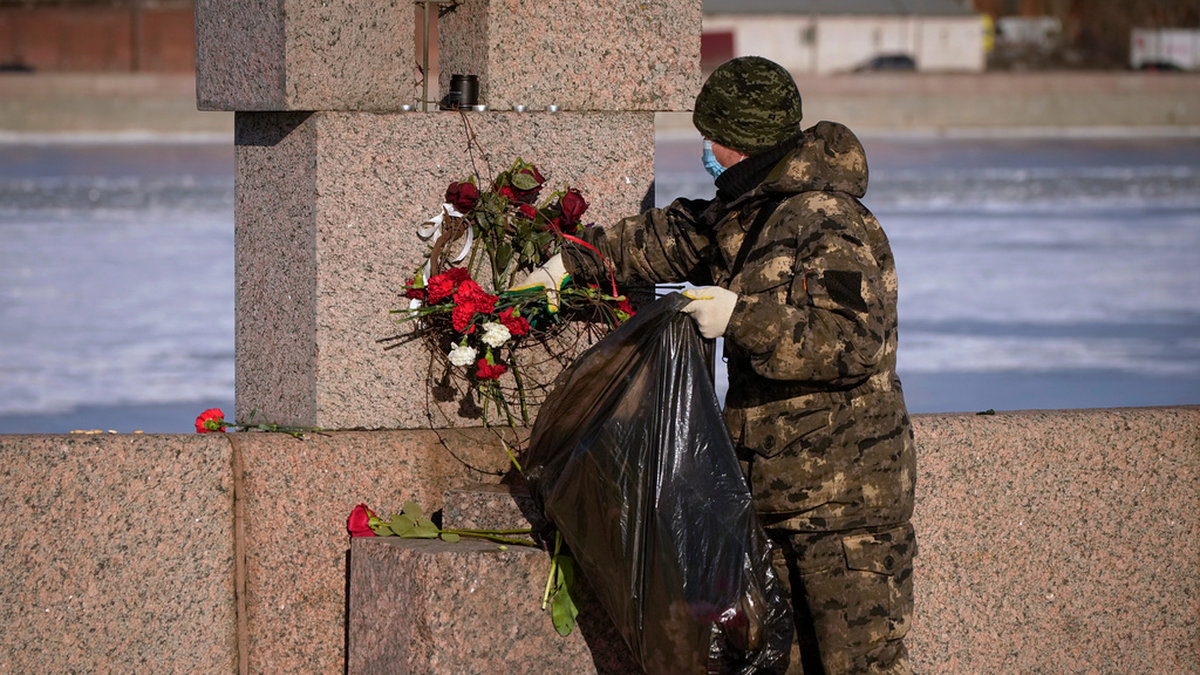 En kommunal arbetare plockar undan blommor som har placerats ut i S:t Petersburg för att högtidlighålla minnet av den döde Aleksej Navalnyj. Bilden togs på måndagen.