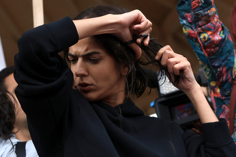 En kvinna klipper sitt hår under demonstrationen i Paris.
