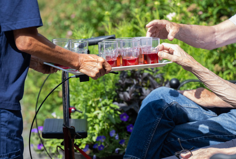 Pensionärer som besöker Brommagårdens dagverksamhet serveras saft när de sitter i solen.