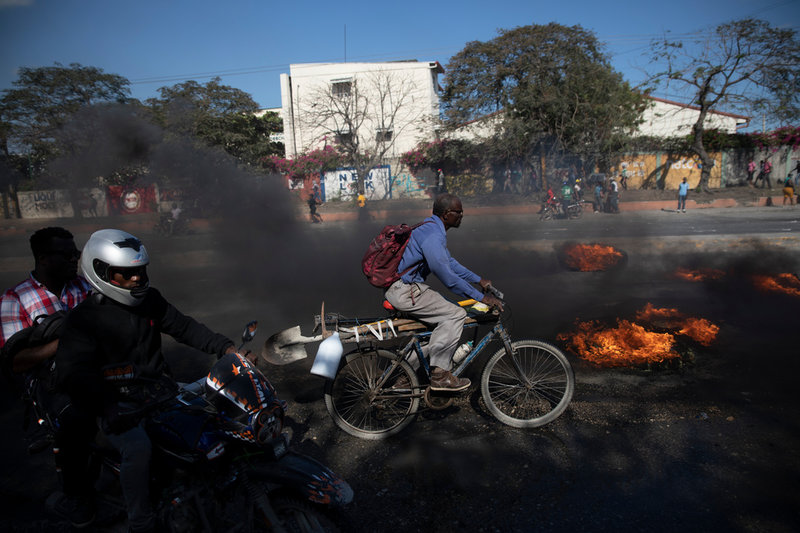 En cyklist tar sig fram bland brinnande däck, vid en fabriksarbetarprotest i Port-au-Prince den 10 oktober. Fabriksarbetarna krävde att deras löner skulle tredubblas till motsvarande ungefär 165 kronor om dagen. Arkivbild.