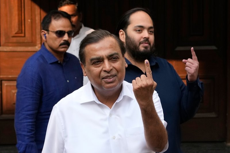 Mukesh och Anant Ambani med fingrar i luften i samband med ett val i Mumbai 2024.