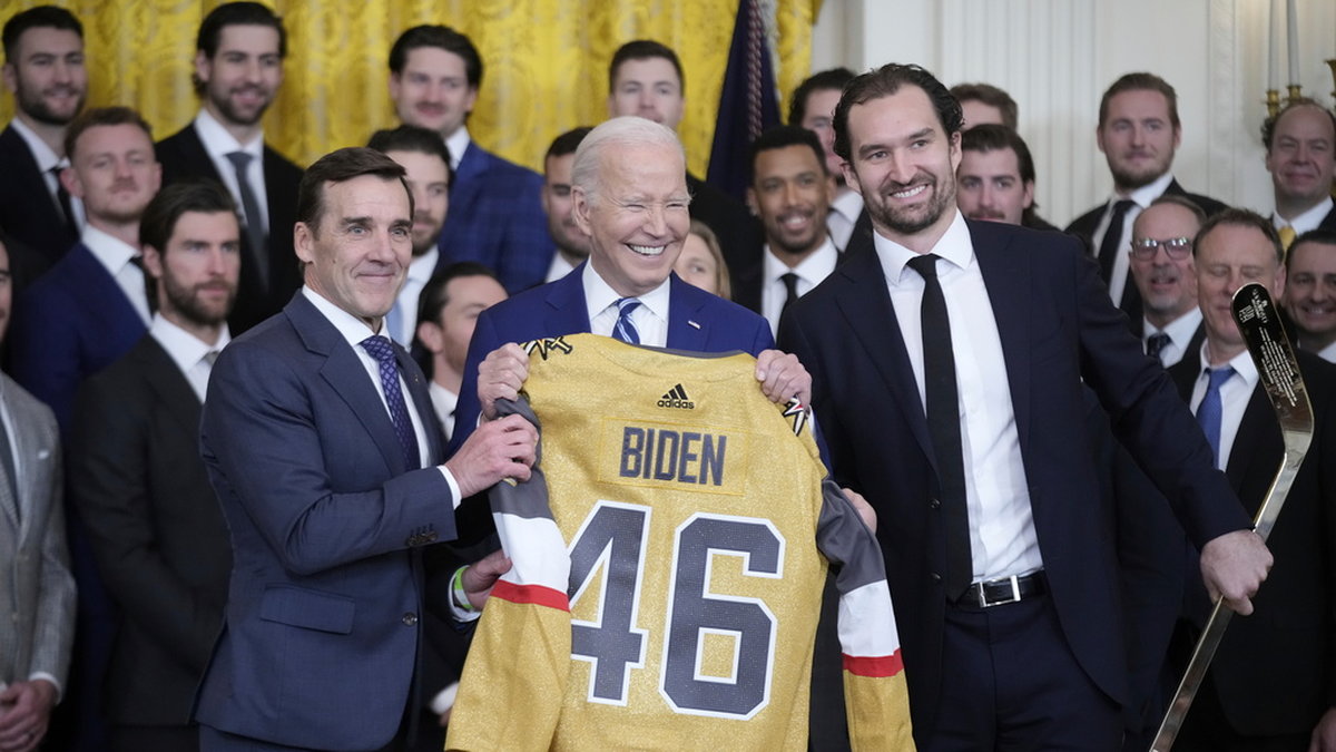 President Joe Biden med en Vegas-tröja. Vegas-kaptenen Mark Stone till höger, överlämnade även en hockeyklubba.