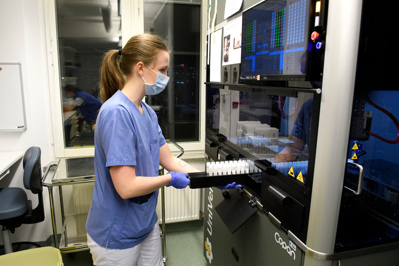 Julia Dahl på masstestningslaboratoriet på Karolinska universitetssjukhuset i Solna skjuter in prover i maskinen UniVerse som med sin robotarm suger upp små droppar och komprimerar proverna till mer hanterbar storlek.