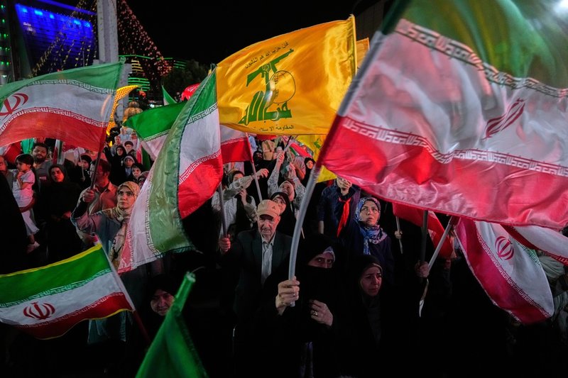 Människor i en regimorganiserad folksamling i Teheran viftar med den islamiska republikens flagga samt med den gula flaggan som tillhör den Iranallierade libanesiska rörelsen Hizbollah. Bilden togs i söndags.