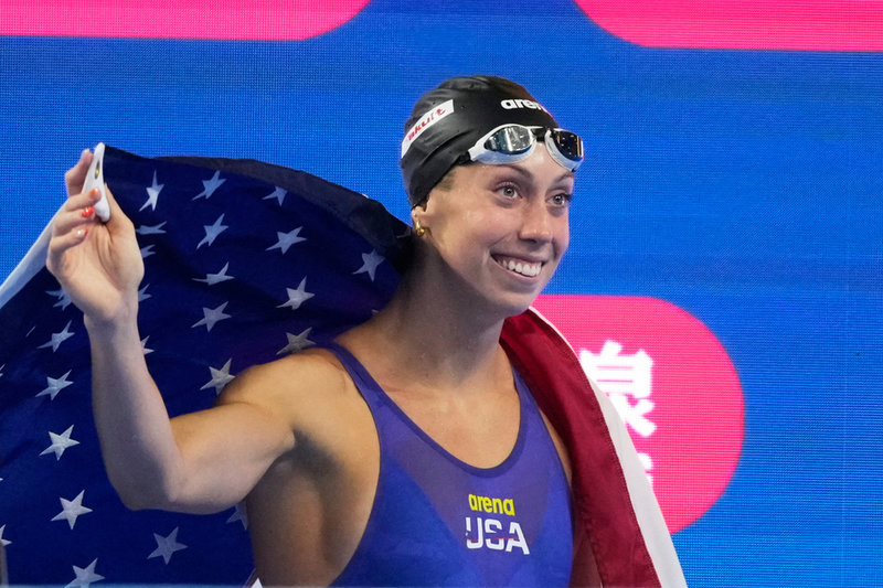 Gretchen Walsh firar, draperad i amerikanska flaggan.