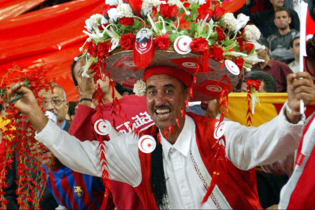 Här firar tunisiska fotbollssupportrar under en match mot Marocko.