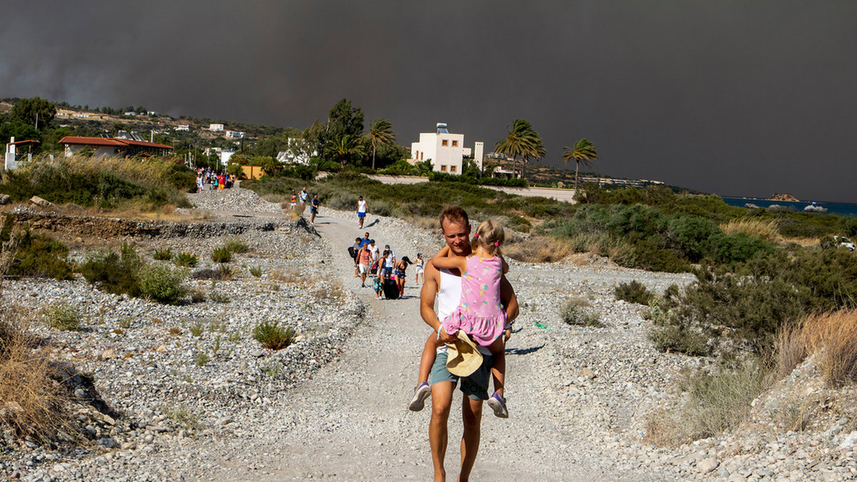 Turister flyr undan bränderna som härjade på Rhodos förra året. Arkivbild.