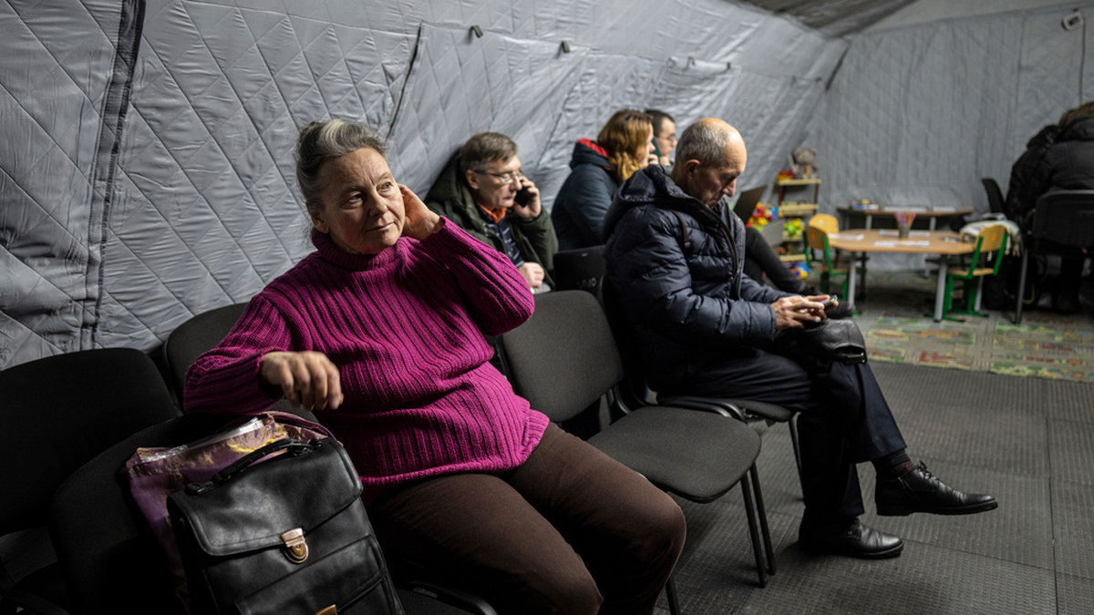 Människor värmer sig och laddar sina mobiltelefoner i ett värmetält i Kiev, Ukraina, under måndagen.