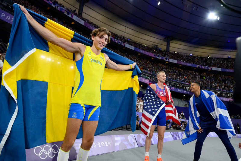 Guldjubel draperad i svenska flaggan i OS i Paris, tillsammans med övriga medaljörerna Sam Kendricks (silver) och Emmanouil Karalis (brons). Arkivbild.