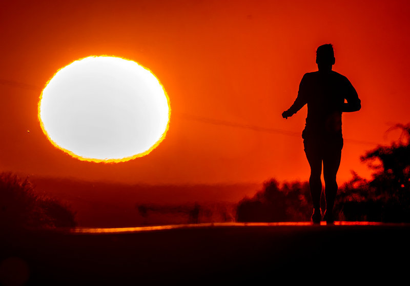 En joggare i soluppgången i Frankfurt i Tyskland den 17 juni. Den röda färgen signalerar att värmen kan vara riskabel, men personen på bilden är anonym och ansiktslös.
