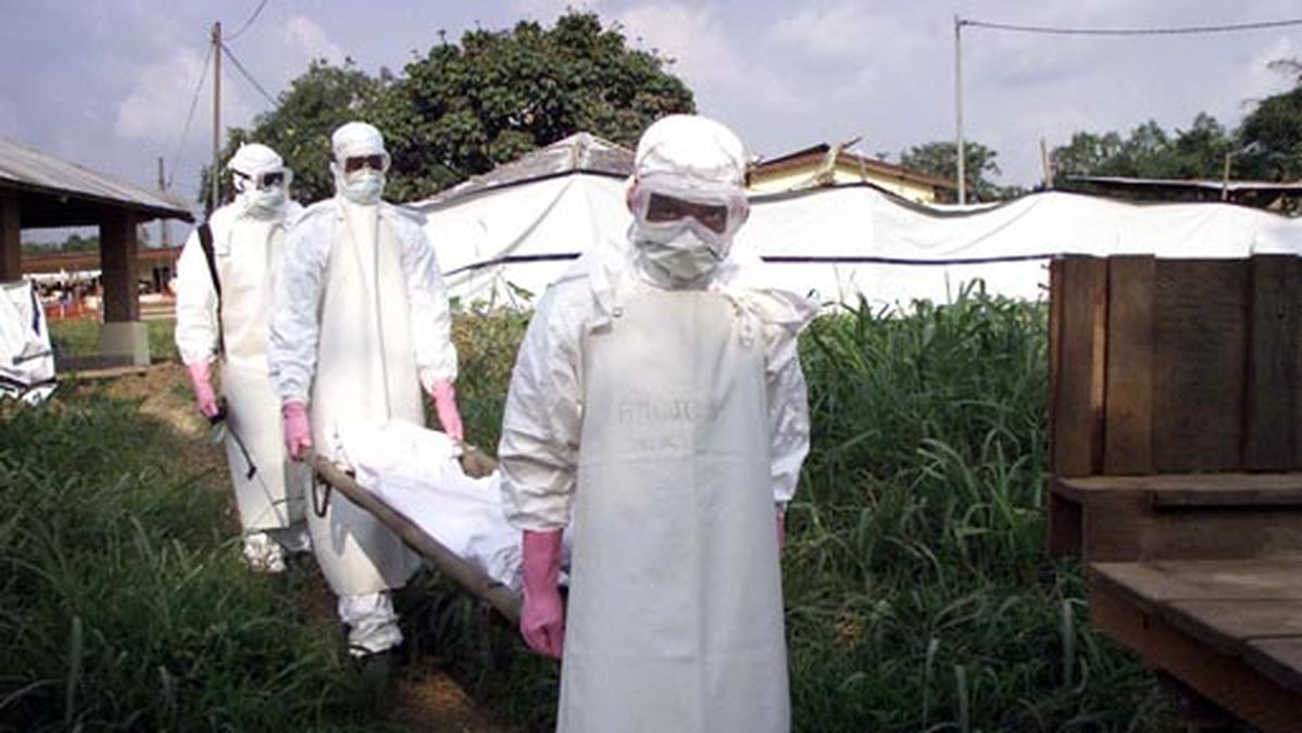 Arbetare i skyddskläder bär en person som har dött av Ebola-smittan.