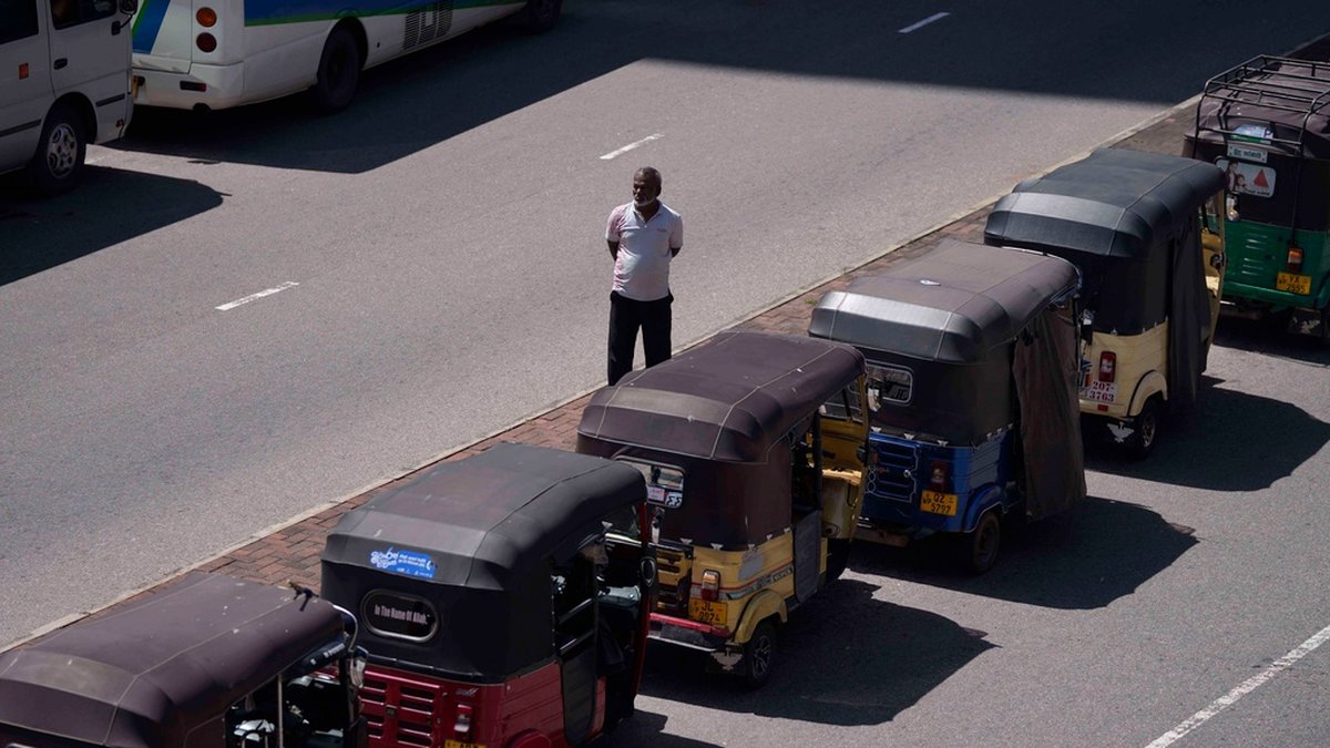 En man står och köar för att få köpa bensin till sin tuk tuk i Sri Lankas huvudstad Colombo.