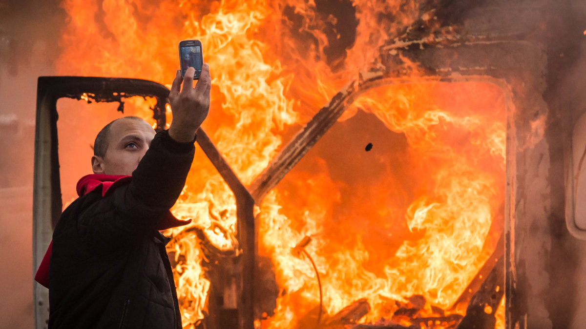 En demonstrant tar en selfie framför en brinnande bil under en demonstration i Bryssel i november. 