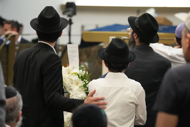 Sörjande i synagogan under begravningen för rabbinen Eli Schlanger. 