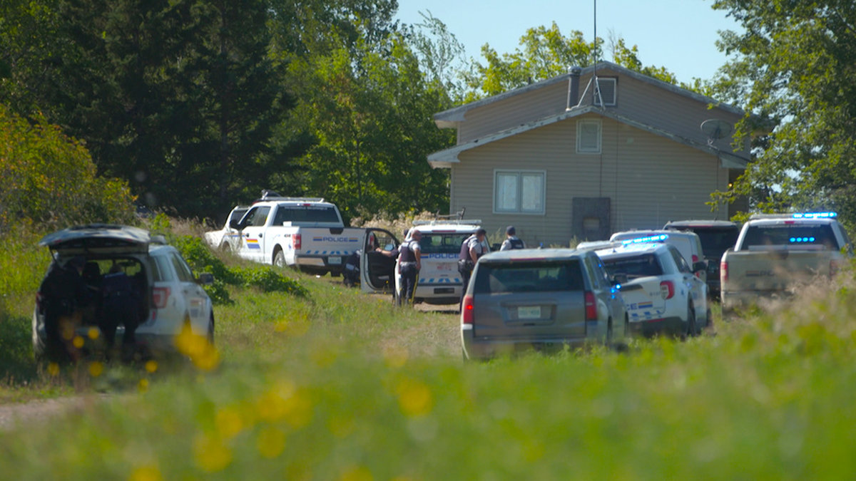 Polisen har omringat en bostad i letandet efter en av de bröder som misstänks för att i söndags ha mördat tio personer i Kanada.