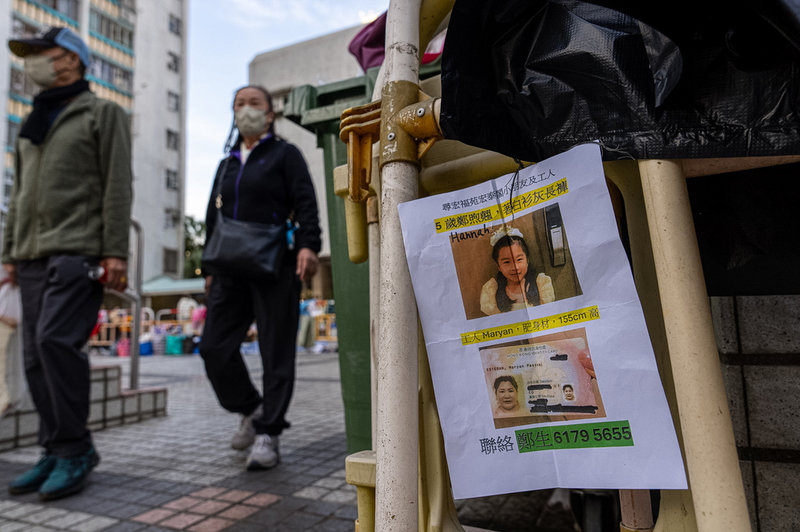En lapp med bilder på två saknade personer har satts upp nära katastrofplatsen i Hongkong. Bild tagen på fredagen.
