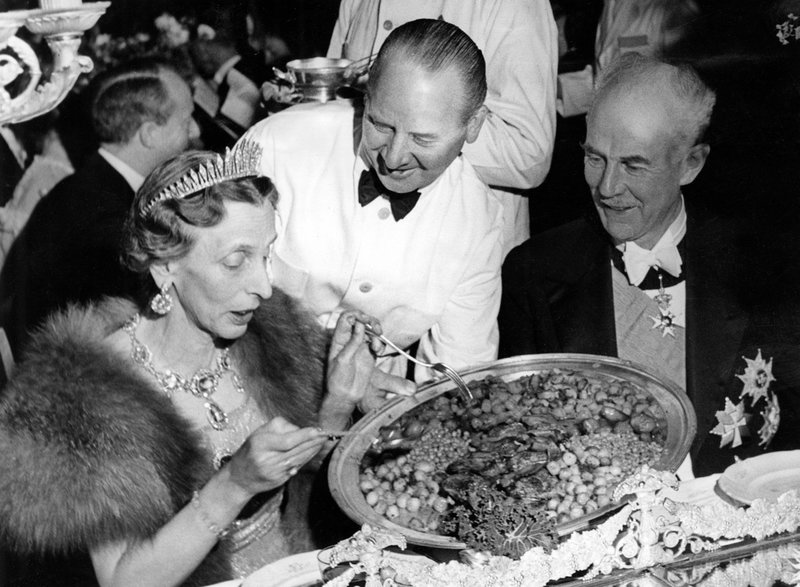 Kronprinsessan Louise tar för sig av den stekta kycklingen med selleri, majrovor, lök och bacon medan riksmarskalk Birger Ekeberg ser på under Nobelbanketten 1947. Arkivbild.