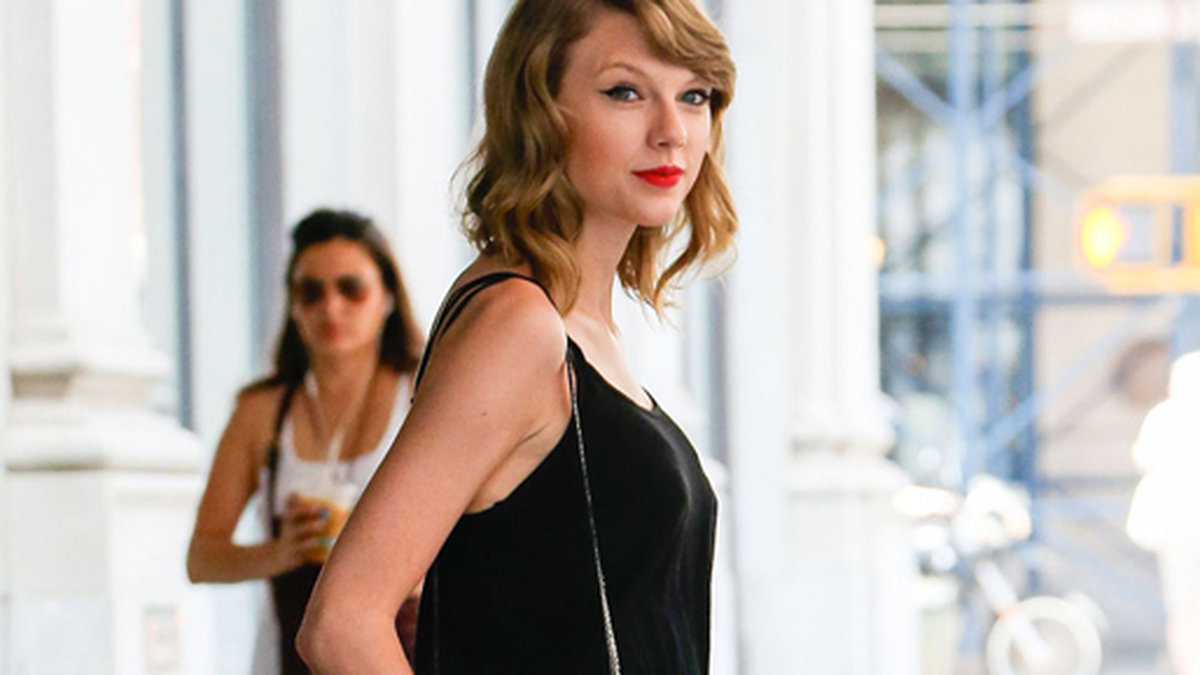 Taylor Swift kör en svart jumpsuit och röda läppar. 