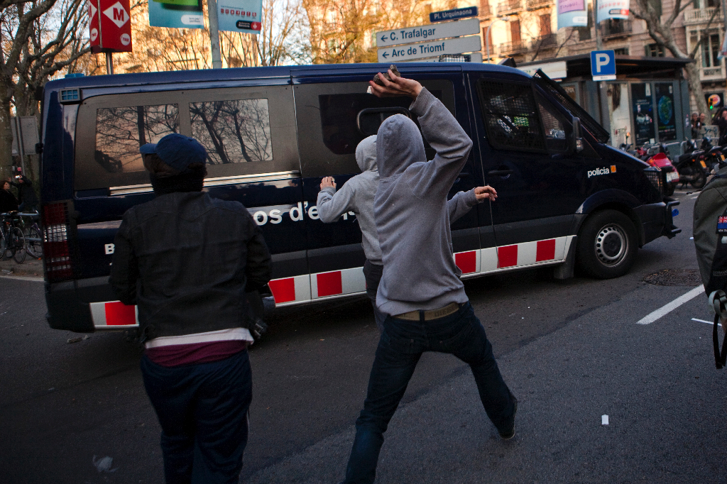 Demonstranter kastar sten på en polisbil.
