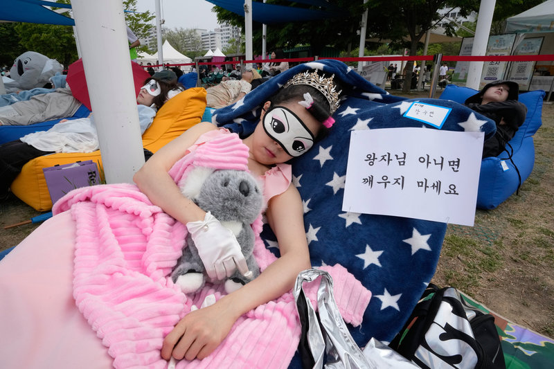 En kvinnlig deltagare tar en tupplur i Seoul. "Väck mig inte om du inte är en prins", står det på skylten.