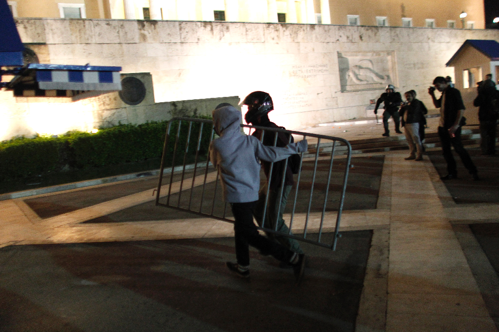 Protestanter bär ett kravallstaket som de senare kastar på polisen. 